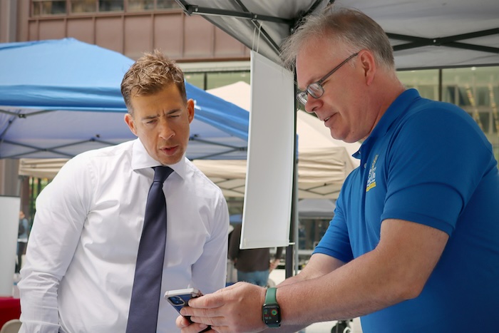 A man in a blue polo shirt in discussion with a man in a white dress shirt and tie.